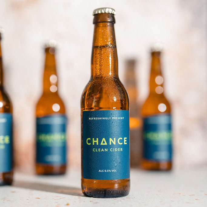 Bottle of Chance Clean  Alcohol-Free Cider with a blue label on a wooden surface.